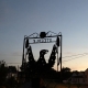 Silhouette of a metal eagle sign reading "STEEPLE" against a dusky evening sky in a village setting.