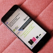 A smartphone on a pink fabric surface displays a news alert about potential thunderstorms and high temperatures.