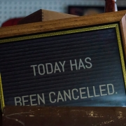 A framed sign reads "TODAY HAS BEEN CANCELLED" in white letters on a dark background.