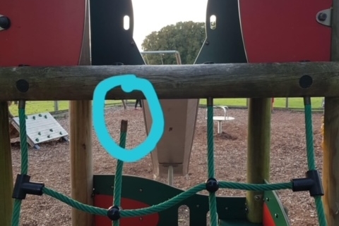 Playground climbing frame with green rope net; a broken rope is ringed in blue in the centre of the image.