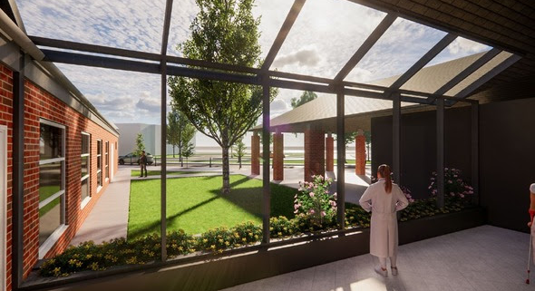 View through large windows to a green courtyard with trees and people walking; one person stands inside.