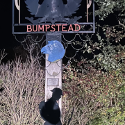 A village sign for Steeple Bumpstead, featuring a bird, wheat, and a soldier silhouette with “Lest We Forget”.
