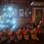 A house decorated with Christmas lights, candy canes, and a Christmas tree outside at night.
