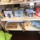 Two shelves with children's books and wooden jigsaw puzzles, next to a green beanbag chair.