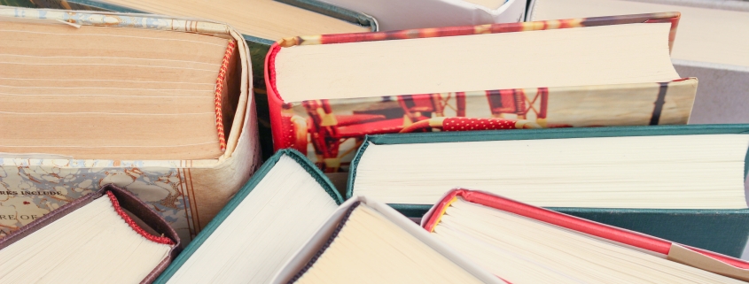 A close-up of several books arranged vertically with their pages and covers visible.